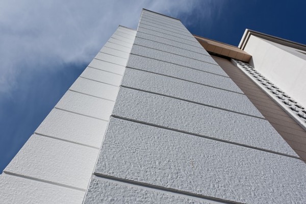 Textured fiber-cement facade panels with horizontal joints, low-angle view